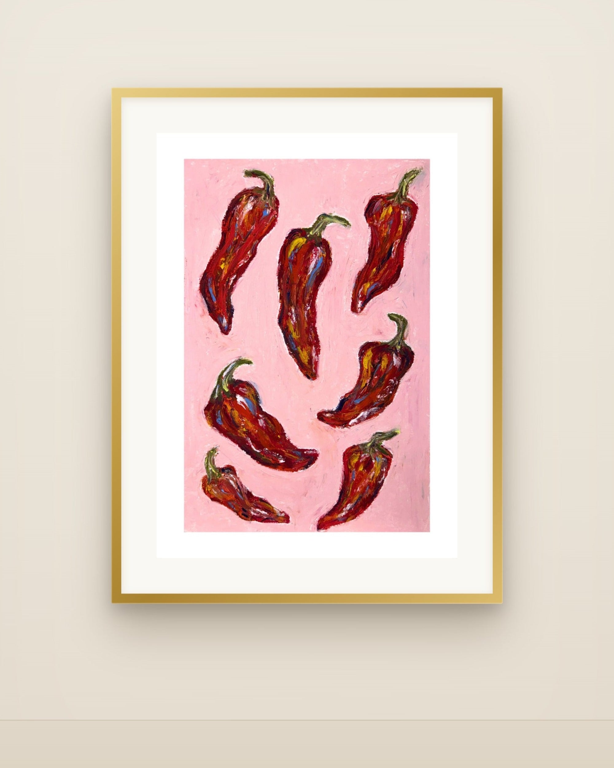 Framed wall art featuring a pink background with illustrated red chili peppers, displayed against a light beige wall.
